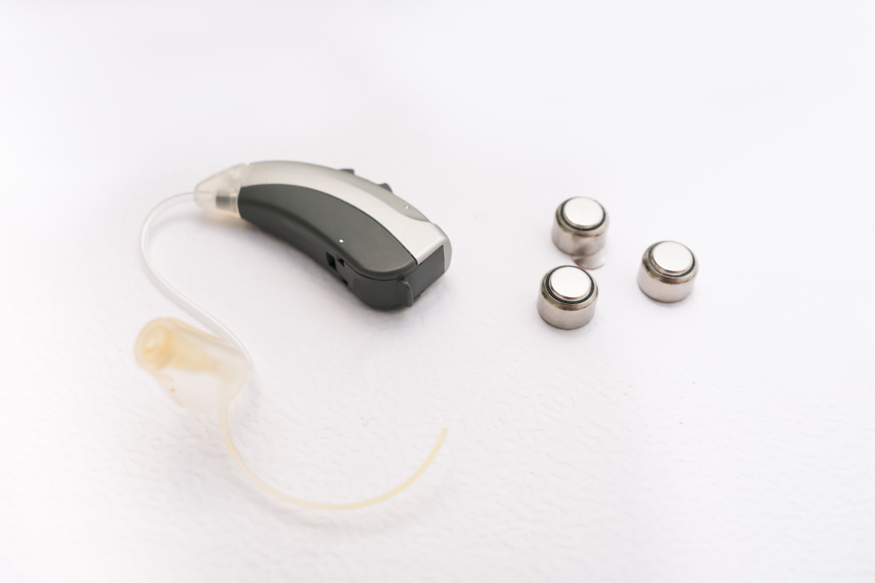 Hearing aid with batteries in white background.
