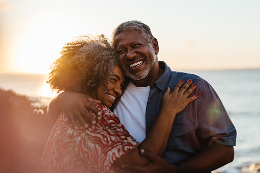 Happy older couple embracing on a beach during a beautiful sunset