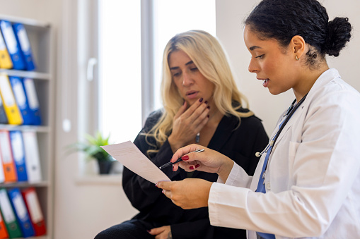 Audiologist reviews hearing test results, or an audiogram, with her patient, who is listening closely.